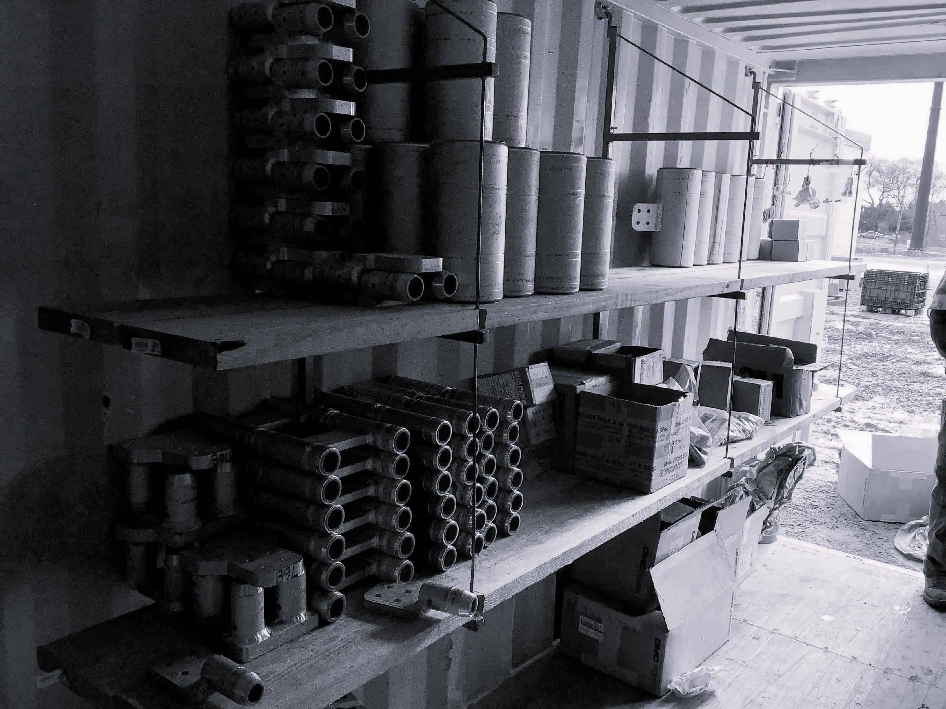 Shelves stocked with metal connectors and fittings inside a storage container.